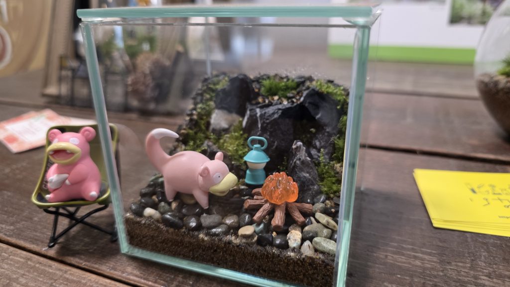 ヤドンのフィギュアと焚き火が配置された苔テラリウムの展示作品